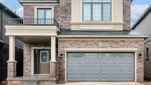 A two-story house with a garage, a balcony, and a brick facade. - Detached 4 Bedroom (Brant)
