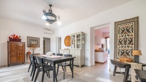 A spacious dining area with a black table and chairs, a wooden cabinet, and a decorative wall piece.