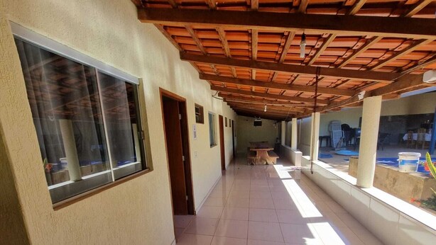 A corridor with tiled flooring, large windows, and a wooden ceiling structure. - MATEUS ALVES DA SILVA (São João da Paraúna)