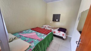 A small, single-room accommodation with a bed, a bedside table, and a wall-mounted shelf. - MATEUS ALVES DA SILVA (São João da Paraúna)