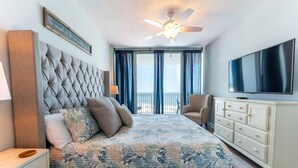 A bedroom with a large bed, a ceiling fan, a TV, a dresser, and a view of the outdoors. - Lighthouse w/ Bunk Room.  3 Pools!  Beachfront-  Free Daily Activities (Gulf Shores)