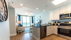 A modern kitchen with a central island, stainless steel appliances, and a view to a balcony. - Lighthouse w/ Bunk Room.  3 Pools!  Beachfront-  Free Daily Activities (Gulf Shores)