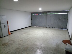 A spacious room with a tiled floor, a closed metal gate, and a refrigerator on the left. - Casa de renta vacacional, amplia, punto estratégico de Cali, ideal para familias (Cali)