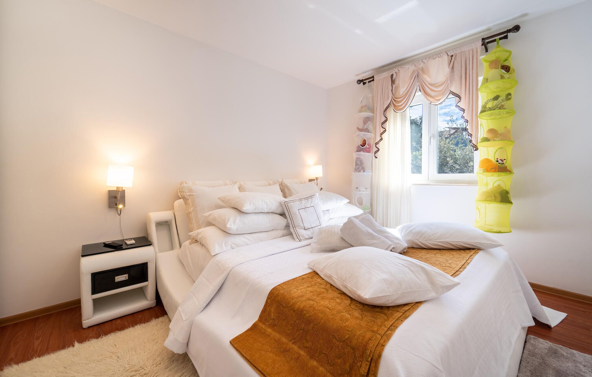 A neatly arranged bedroom with a bed, bedside tables, and a window with curtains.