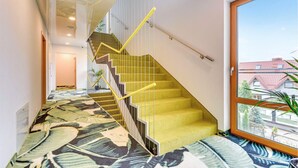 Ein modernes Interieur mit einer Treppe, einem gemusterten Teppich und einem großen Fenster mit Blick ins Freie.