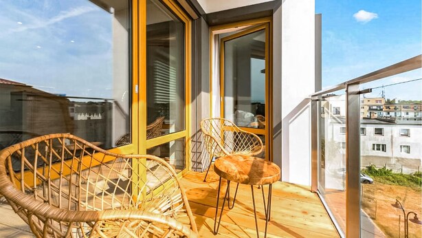 Ein Balkon mit Korbmöbeln und Blick auf die Stadt.