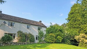 A two-story house with a stone facade, multiple windows, and a well-maintained lawn.