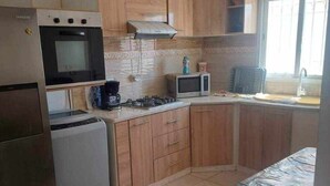 A compact kitchen with a refrigerator, microwave, stove, and a small sink.