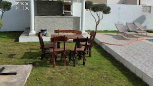 A patio area with a table and chairs, a grill, and a small tree.