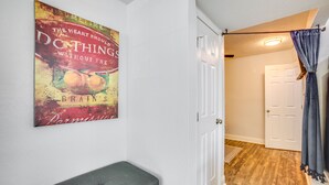 A hallway with a door, a bench, and a poster on the wall. - < 1 Mi to Downtown Conroe: Charming Apartment (Conroe)