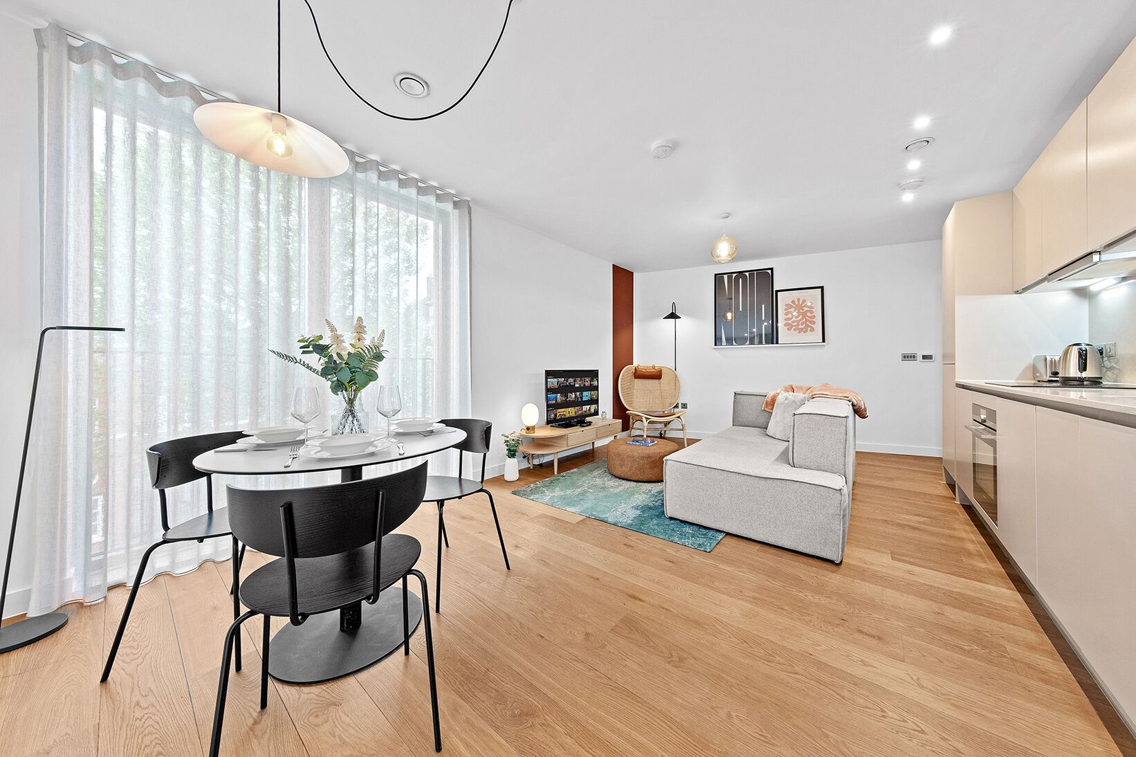 Un salon moderne comprenant une table à manger, un canapé et un coin cuisine.