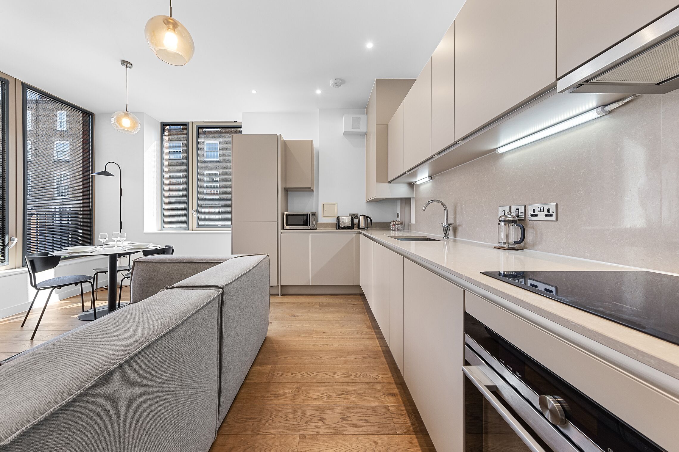A modern kitchen with a central island, built-in appliances, and a dining area with a view.