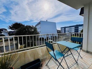 Enjoy the view from this balcony with a white railing, blue table, and comfortable seating.