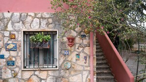 Un edificio de piedra con una ventana que muestra plantas, una escalera y varios platos decorativos en la pared.