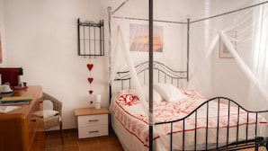 Un dormitorio con cama con dosel, mesita de noche, silla y escritorio.