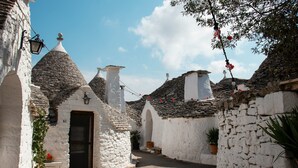 Una calle estrecha con edificios blancos, techos de piedra y cielo despejado.