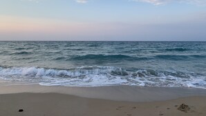 Una playa con olas acercándose a la orilla bajo un cielo parcialmente nublado.