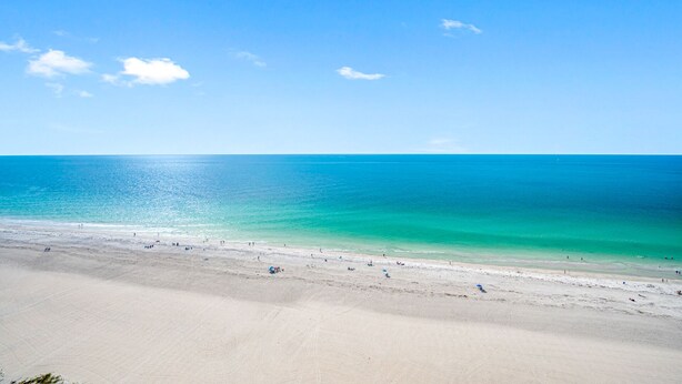 Une plage à l’eau turquoise et limpide, bordée d’un rivage sablonneux.