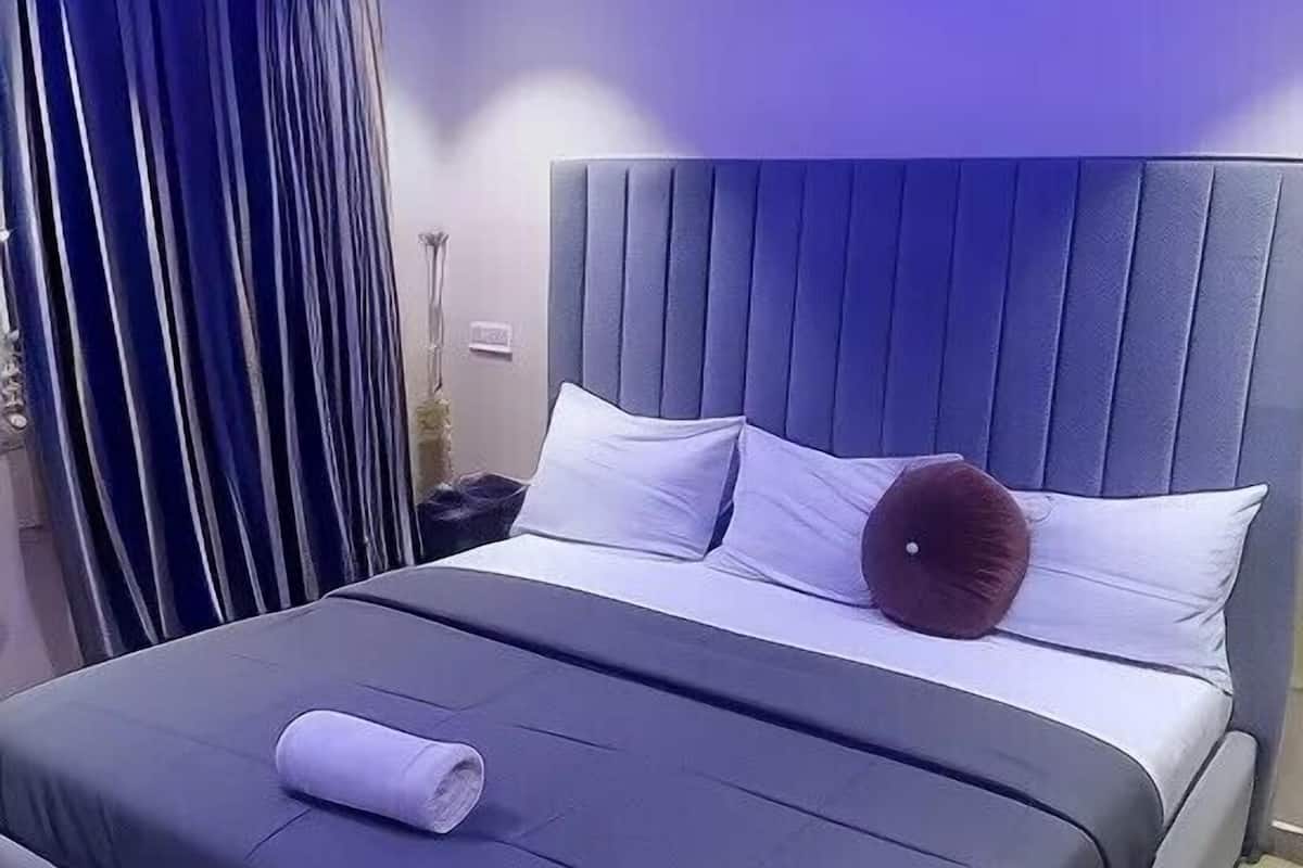 A modern bedroom with a large bed, a headboard, and a nightstand.