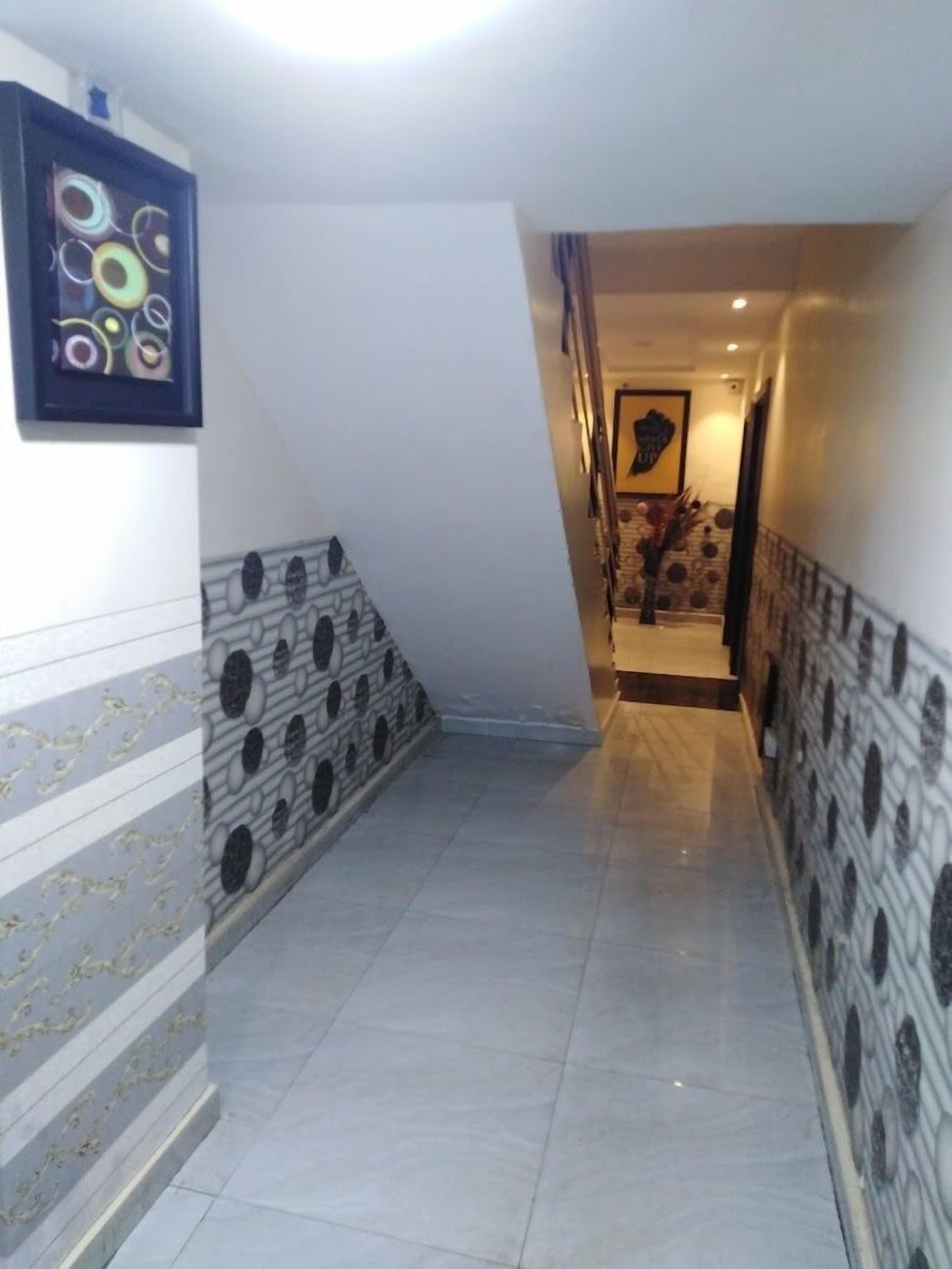 A hallway with patterned walls and a tiled floor, leading to a staircase.