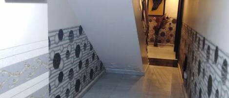 A hallway with patterned walls and a tiled floor, leading to a staircase.