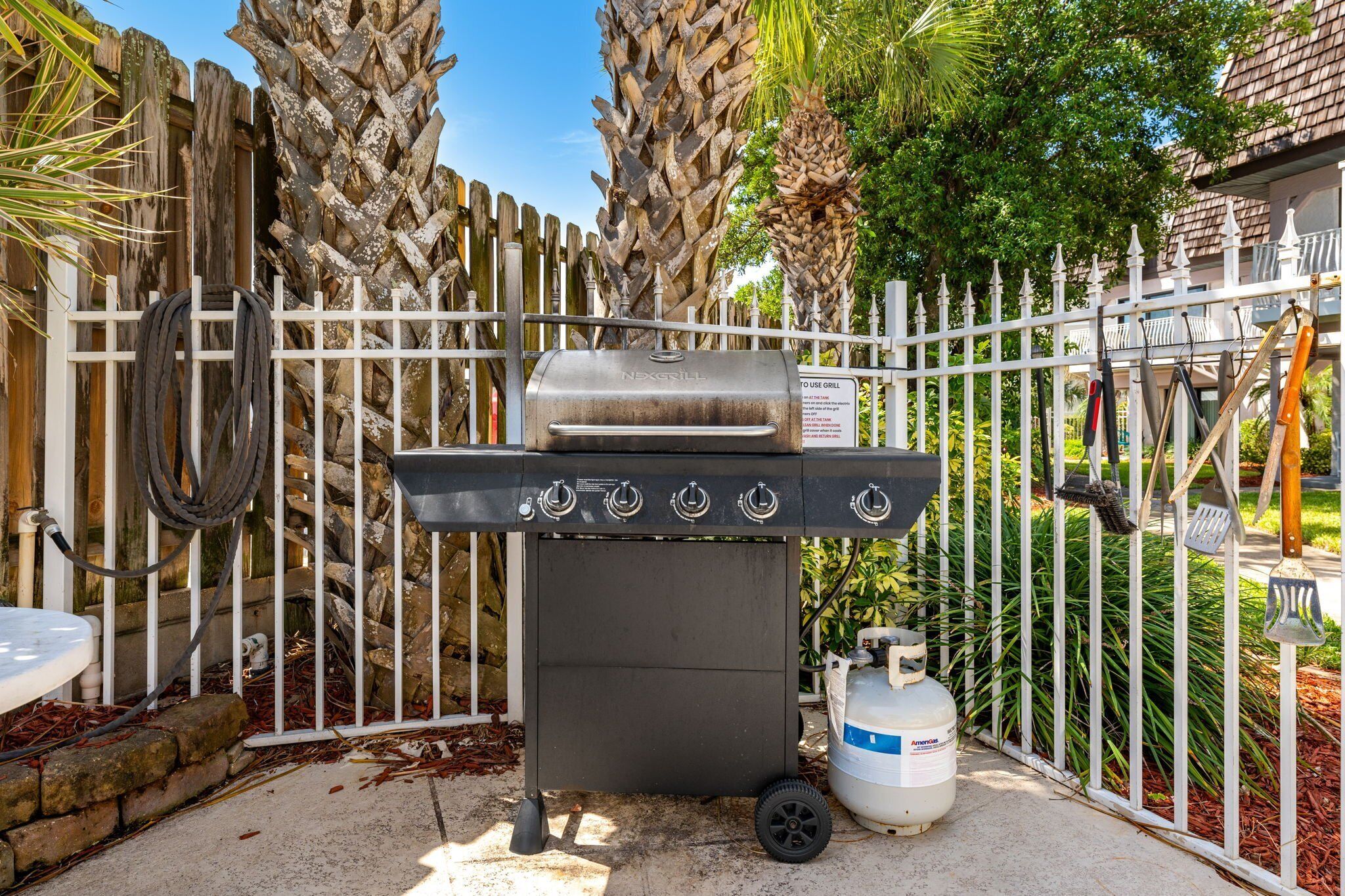 Una parrilla portátil con tanque de gas, manguera y un cartel que indica que es para asar.