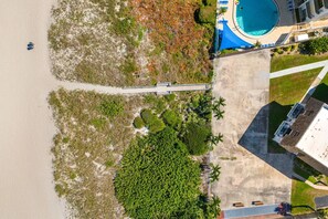 Vue aérienne d’un complexe hôtelier doté d’une plage, d’une piscine et d’un pont reliant différentes zones.