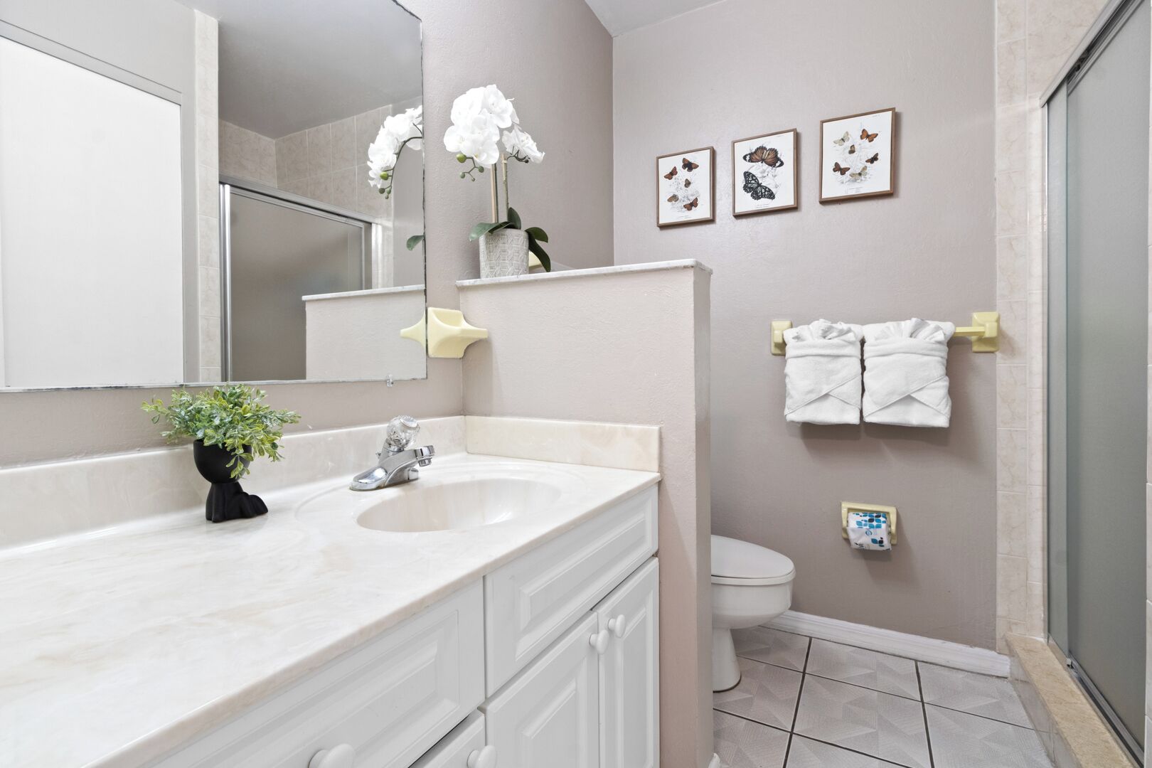 Une salle de bain équipée d’un lavabo, d’un miroir, de toilettes et d’un porte-serviettes.