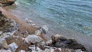 Uma costa rochosa com água cristalina e uma vista distante do mar.