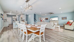 Un vaste espace de vie comprenant une table à manger, des chaises blanches et un canapé.