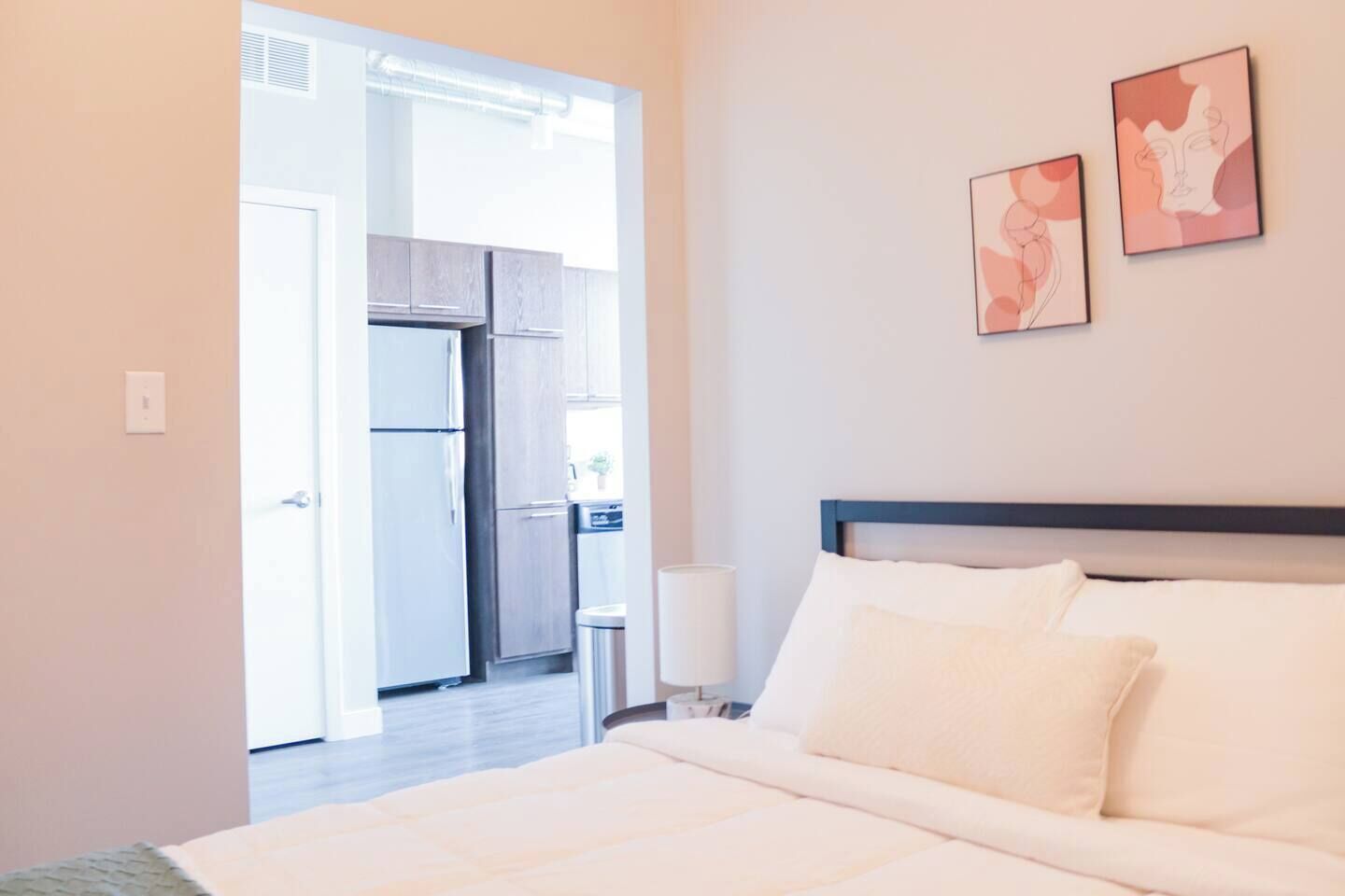 A hotel room with a bed, a nightstand, a lamp, and two wall art pieces.