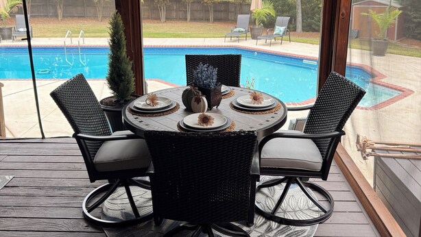 Une terrasse couverte équipée d’une table de billard, de chaises et offrant une vue sur la piscine du jardin.
