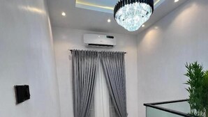 Una escalera moderna con barandillas de vidrio, un candelabro y cortinas grises.