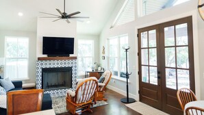 A spacious living room with a fireplace, comfortable seating, and a large TV. - Day Drippin’ Farmstay (Dripping Springs)
