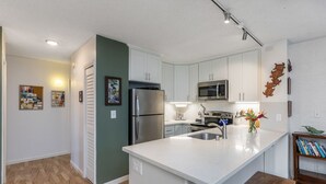 Une cuisine moderne avec des meubles blancs, des appareils en acier inoxydable et un îlot central en bois.