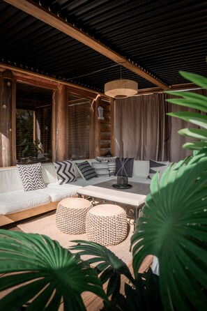A covered outdoor seating area with a sofa, cushions, and a table. - Private Cabin Resort l Pool • Hot Tub • Sauna Wanderlust Cabin (Lodi)