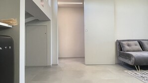 Una habitación de hotel moderna con un armario de puerta corredera, un sofá gris y un piso de color claro.