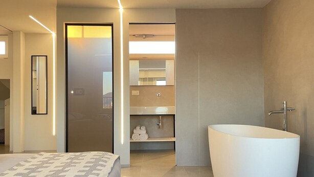 Un baño moderno con una bañera independiente, un lavabo empotrado y un espejo sobre el lavamanos.