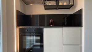 Una cocina moderna con horno empotrado, armarios blancos y encimera negra.