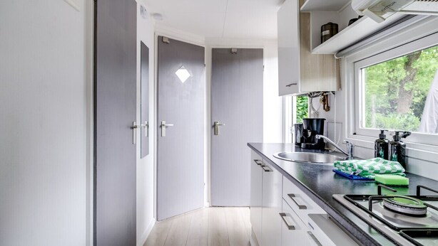 Una cucina moderna con finestra, elettrodomestici in acciaio inossidabile e vista sul verde.