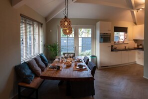 A dining area with a wooden table set for four, surrounded by cushioned benches.