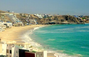 A coastal town with beachfront properties, a sandy beach, and a clear blue sea.