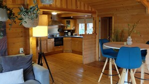 A cozy wooden cabin interior with a dining area, kitchen, and seating space.