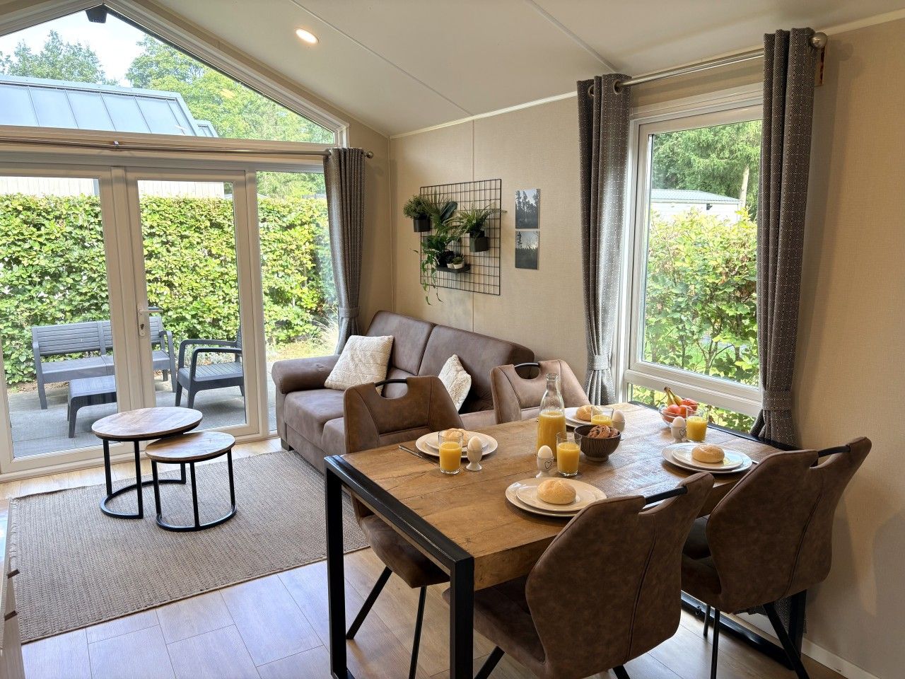 A dining area with a table set for breakfast, a sofa, and a view through a glass door.