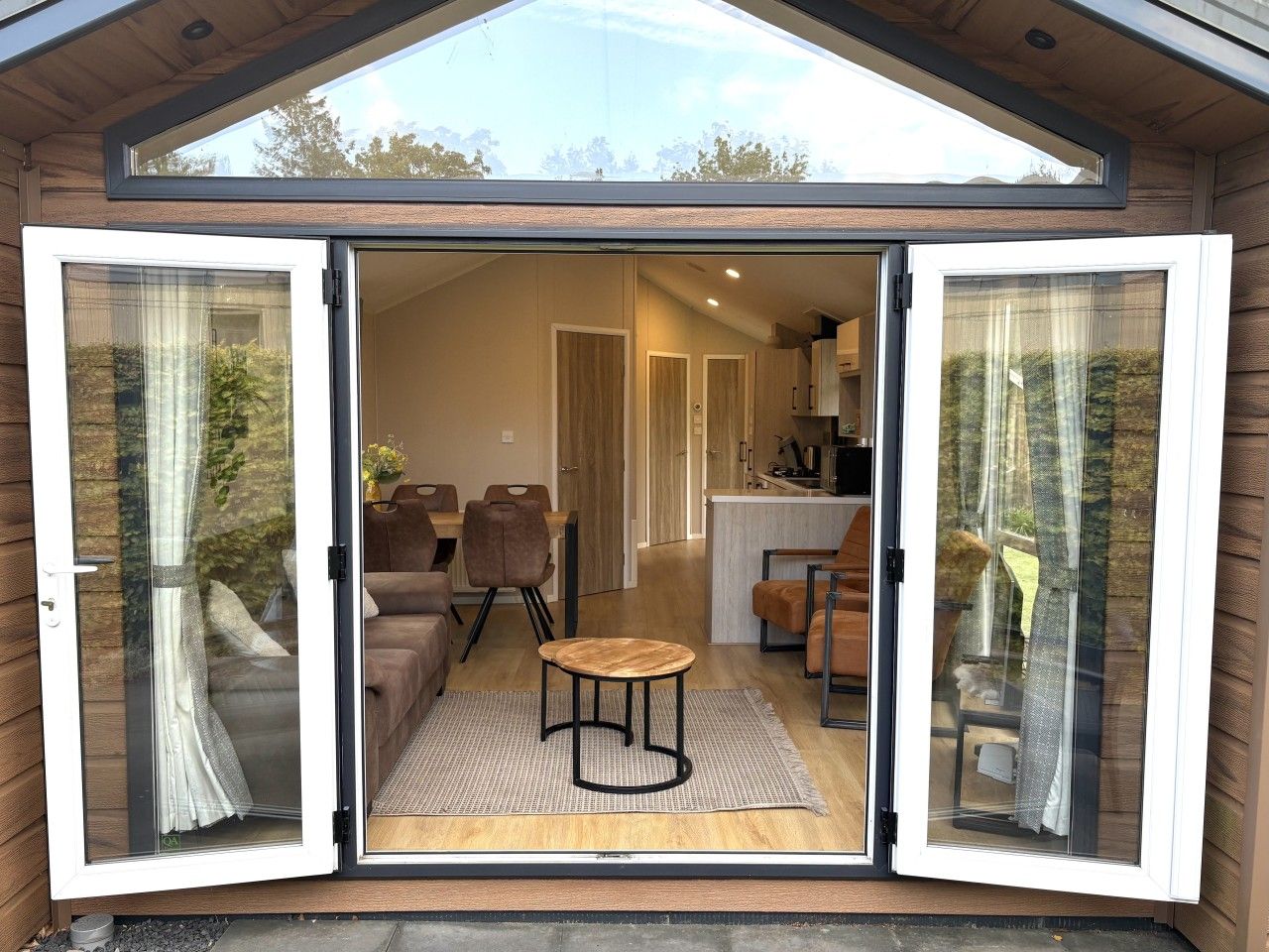 A modern interior with a dining area, sofas, and a kitchen visible through a glass door.