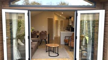 A modern interior with a dining area, sofas, and a kitchen visible through a glass door.