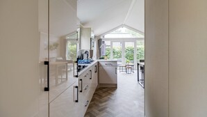 Una cocina moderna con suelo de espiga, armarios blancos y un amplio ventanal con vistas a zonas verdes.