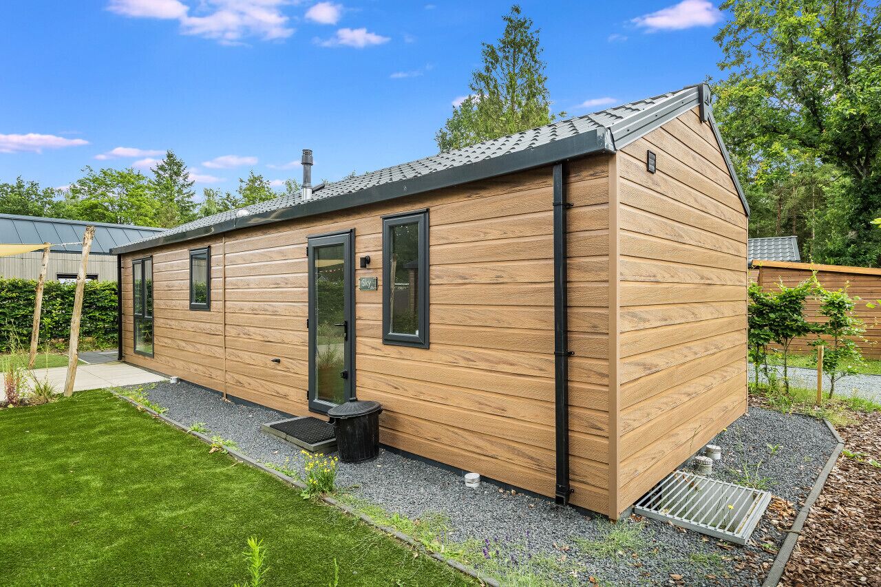 A modern wooden cabin with a sloped roof, large windows, and a small porch area.