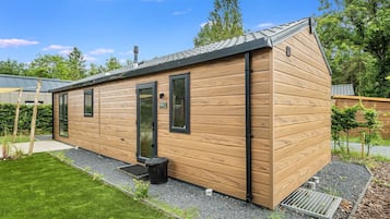 A modern wooden cabin with a sloped roof, large windows, and a small porch area.