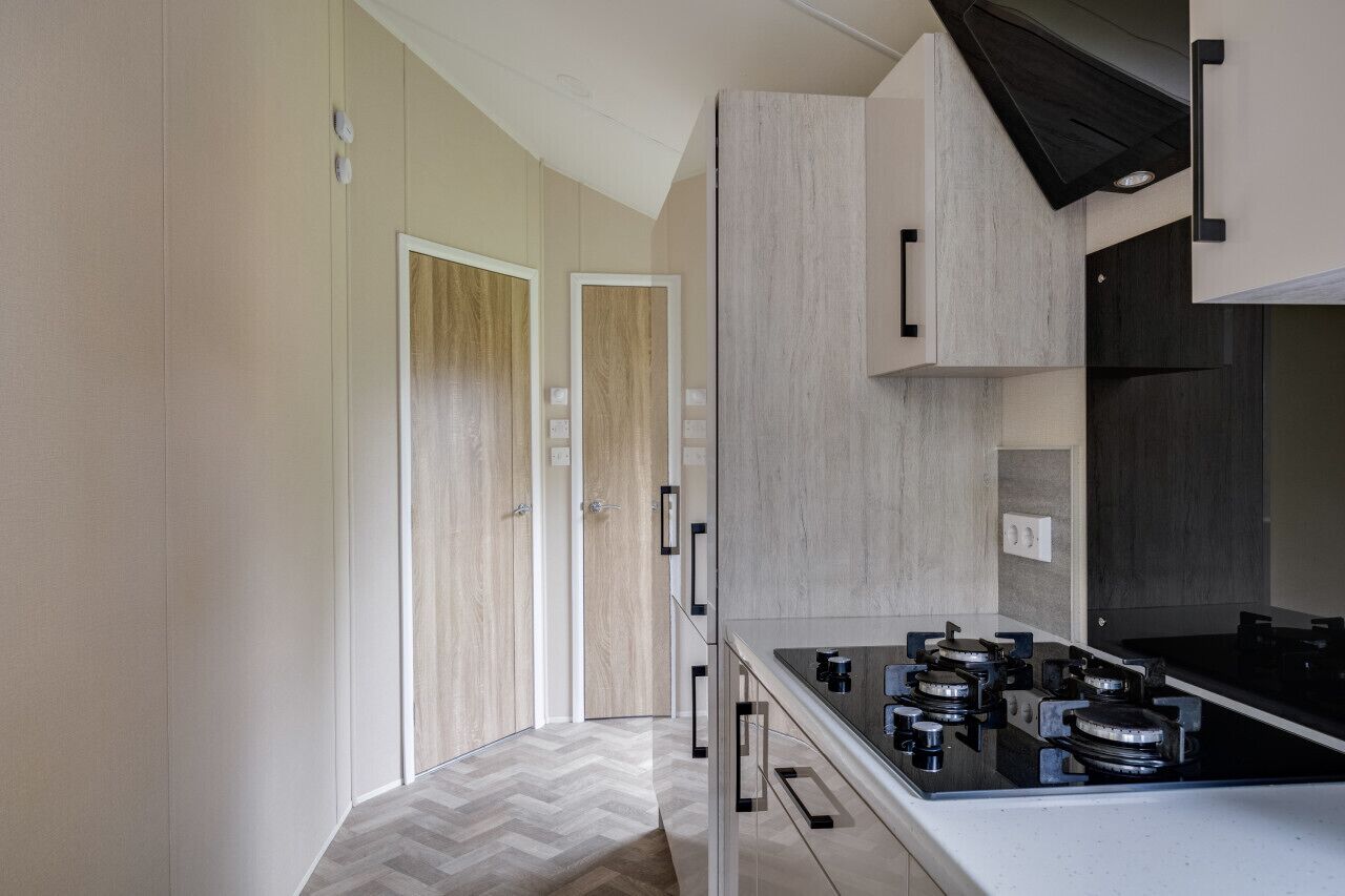 A modern kitchen with a black stove, wooden cabinets, and a herringbone-patterned floor.